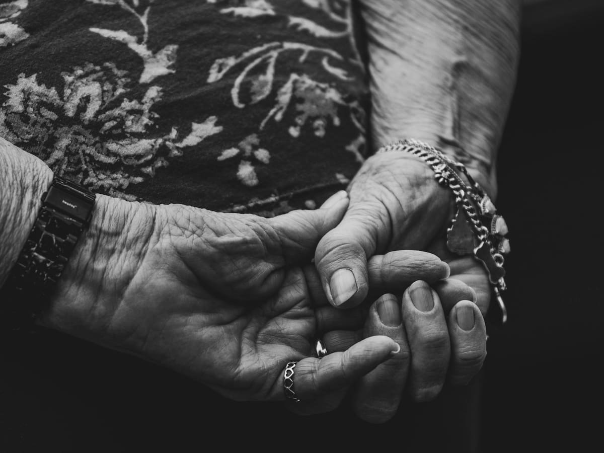 an older woman holding the hand of a younger woman