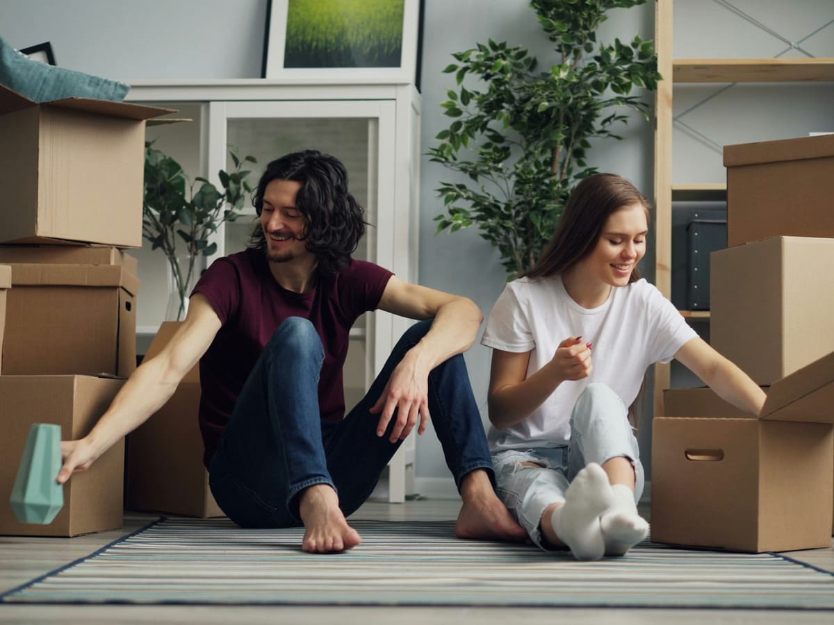 a man and a woman sitting on the floor surrounded by boxes