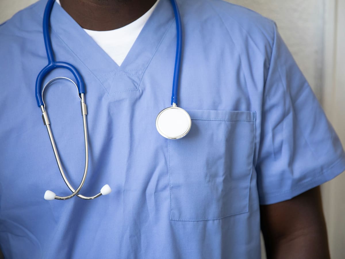 A person in blue medical scrubs with a stethoscope around their neck