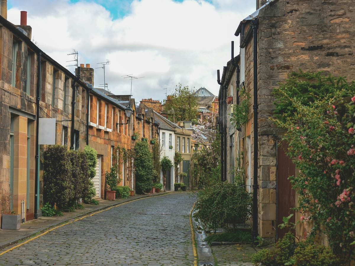 Cobblestone street lined with stone houses and greenery
