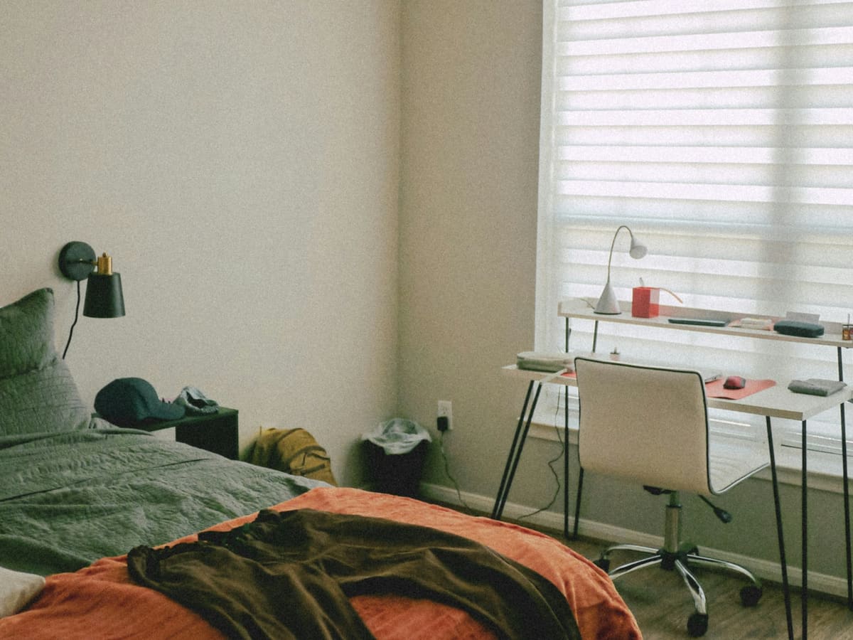 a bedroom with a bed, desk, and chair