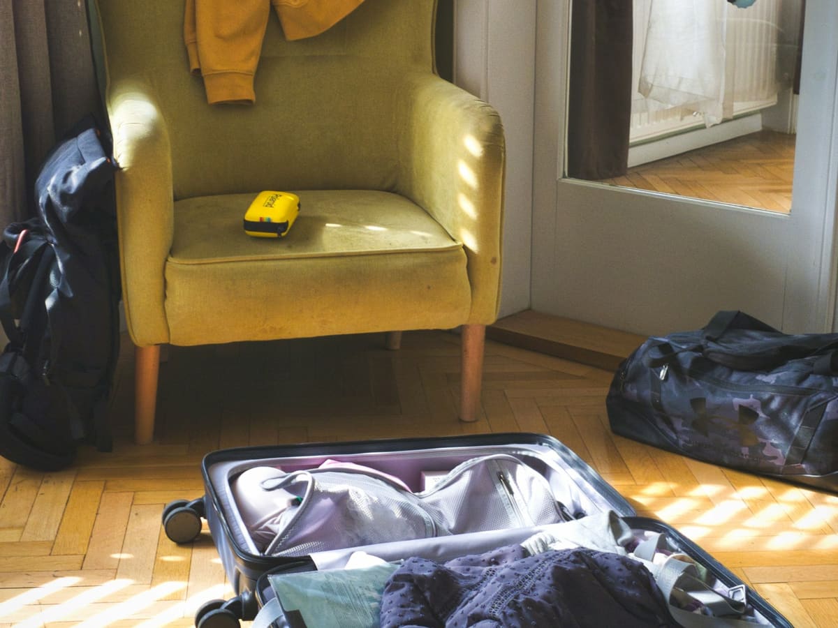 Open suitcase with clothes and armchair in a room